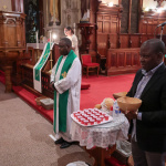 (Edmonton, AB) Le Père Philippe Insoni, pasteur de l'Église catholique de Saint-Joachim, accueille les invités avec une calebasse d'eau. 